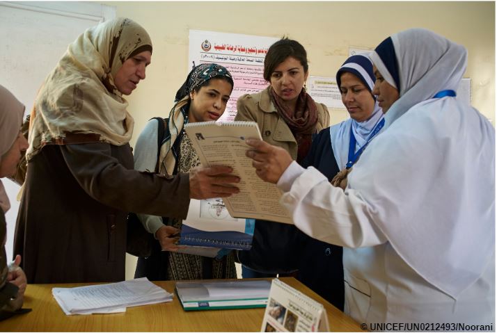 Women gathered around another colleague showing materials and explaining to them